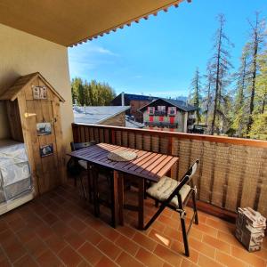 a balcony with a wooden table and chairs on a deck at Studio Hyper centre Valberg in Valberg +8 photos