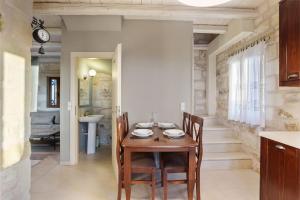 a dining room with a wooden table and chairs at Villa Thalia St George Retreat BY APOKORONAS-VILLAS in Kókkinon Khoríon