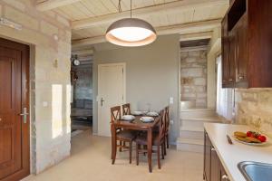 una cucina con tavolo e sedie in una stanza di Villa Thalia St George Retreat BY APOKORONAS-VILLAS a Kókkinon Khoríon