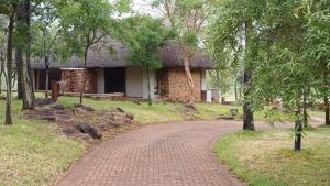 einen Backsteinweg vor einem Haus mit Bäumen in der Unterkunft Ilanga Safari Lodge - Welgevonden Game Reserve in Vaalwater