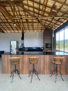 uma cozinha com três bancos de bar em frente a um balcão em Casa vista da serra em São João del Rei