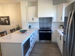 a kitchen with white cabinets and a black stove at Entire4BedroomHomeKingParkingKitchenWasherDryerFastWiFi in Calgary