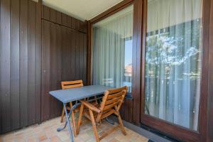 una mesa y sillas en un balcón con ventana en Ferienwohnpark Immenstaad am Bodensee Ein-Zimmer-Apartment 55 11 en Immenstaad am Bodensee