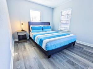a bedroom with a bed with blue sheets and a wooden floor at Elegant 1Bed Montrose-CinqueTerre@TheItalianPlaza in Houston