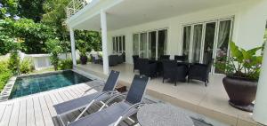 a patio with a table and chairs next to a pool at Villa Blanc - Chateau Elysium in Beau Vallon
