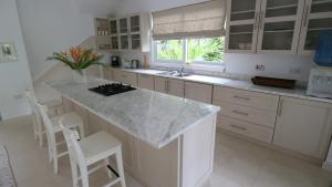 a kitchen with a marble counter top and white cabinets at Villa Blanc - Chateau Elysium in Beau Vallon +8 photos