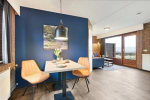 a dining room with blue walls and a table and chairs at Summio Vakantiepark Reevallis in Vijlen