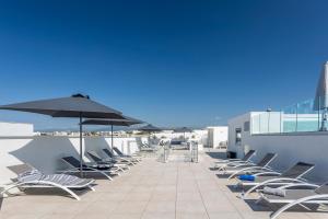 une rangée de chaises et de parasols sur un toit dans l'établissement Nemea Appart Hotel Nice Arenas Aéroport, à Nice