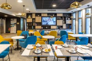 uma sala de jantar com mesas e cadeiras e uma televisão em Nemea Appart Hotel Nice Arenas Aéroport em Nice