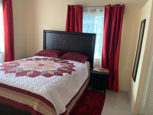 a bedroom with a bed with red curtains at Quiet 2-bed property within the centre of city in Port-of-Spain
