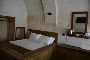 um quarto com uma cama com lençóis brancos e um espelho em MASAL CAVE SUITES OTEL em Ürgüp