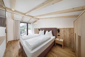 Un dormitorio con una gran cama blanca y una ventana en Schattmair Hof en Tirolo