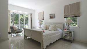 a white bedroom with a bed and a chair at Les Jolies Eaux Villa - Chateau Elysium in Beau Vallon
