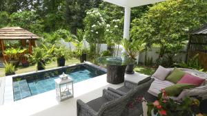 a patio with a pool and a table and chairs at Les Jolies Eaux Villa - Chateau Elysium in Beau Vallon