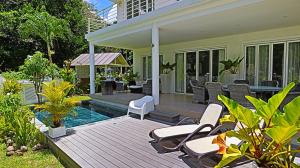 a house with a deck with chairs and a swimming pool at Les Jolies Eaux Villa - Chateau Elysium in Beau Vallon