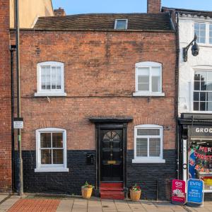 a brick building with a red door on a street at Town Centre Cottage 3 Bedroom inc Parking (1 car) in Shrewsbury