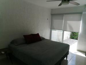 a bedroom with a bed with a fan and a window at Residencia Maya con Hermosa Alberca y Jardines in Mérida