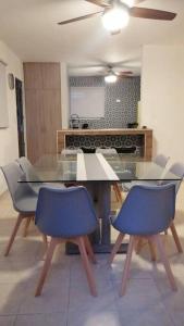 a dining room with a glass table and blue chairs at Residencia Maya con Hermosa Alberca y Jardines in Mérida