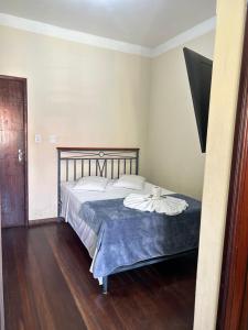um quarto com uma cama grande e um cobertor azul em Hotel Chão Mineiro em São Tomé das Letras