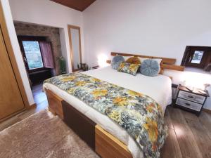 a bedroom with a large bed with a blanket on it at Casa do Penedo Castle House in Linhares