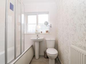 a white bathroom with a toilet and a sink at Clyd Fan in Harlech +28 photos