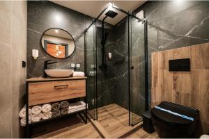 ein Bad mit einer Dusche, einem Waschbecken und einem Spiegel in der Unterkunft Садиба на Кодимі 