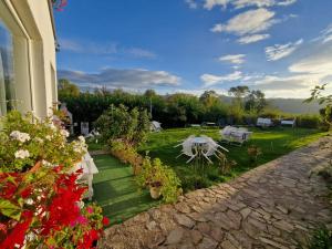 a house with a garden with flowers and a table at Pensiunea Poezii Alese in Valea Drăganului