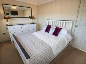 een slaapkamer met een groot wit bed met paarse kussens bij 25 Maes Collen in Llangollen