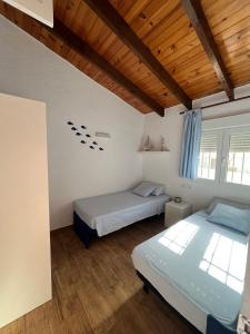 zwei Betten in einem Zimmer mit Holzdecken in der Unterkunft Denia, playa y ciudad in Denia