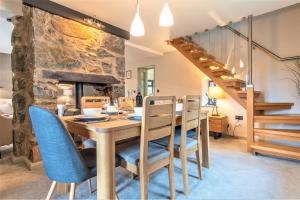 a dining room with a table and chairs and a stone fireplace at The Crossing Cottage in Pwllheli
