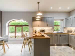 a kitchen with white cabinets and a island with bar stools at 2 bed in Hamsterley 80004 in High Etherley