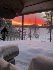 a view of a snow covered yard with a sunset at Villa Kuiske in Kuusamo