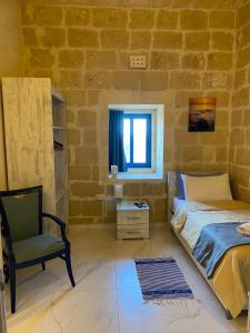 a bedroom with a bed and a chair in a room at Fiftyfour West Boutique Living in Għarb