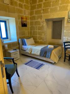 a bedroom with a bed in a brick wall at Fiftyfour West Boutique Living in Għarb