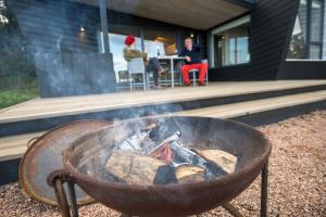 a fire pit in front of a house with two people at Off Grid Travel at Cambo Estate in St Andrews