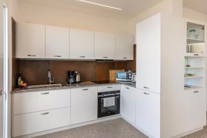 una cocina blanca con armarios y electrodomésticos blancos en Casa Serena, en Torri del Benaco