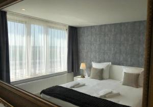 a mirror reflecting a bedroom with a bed and a window at Acropolis - Luxury Appartments I Hotelservice and FREE parking in Middelkerke