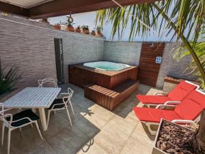 une terrasse avec un bain à remous, une table et des chaises dans l'établissement Cobertura Duplex/Penthouse em Copacabana, à Rio de Janeiro