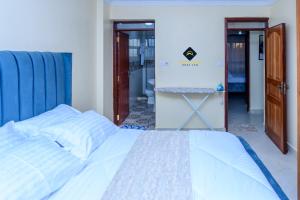 a bedroom with a white bed with a blue head board at Jalde Heights, Limuru Road, 178, Nairobi City, Nairobi, Kenya in Nairobi