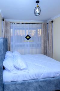 Schlafzimmer mit einem weißen Bett und einem Fenster in der Unterkunft Jalde Heights, Limuru Road, 178, Nairobi City, Nairobi, Kenya in Nairobi