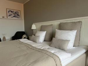 uma cama grande com lençóis brancos e almofadas em Hotel Strandly Skagen em Skagen