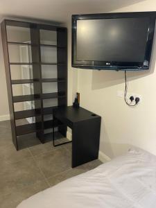 a bedroom with a tv on the wall and a black desk at 50A Green Lane in Cranford