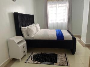 a bedroom with a bed with a black headboard and a window at Garden estate Thika road furnished home in Nairobi