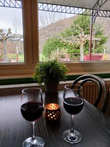 twee glazen rode wijn op een tafel met een raam bij Hotel Rêve de la Vallée in Blesle