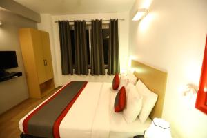 um quarto com uma cama com lençóis brancos e almofadas vermelhas em BK Studio And Rooms Near Huda City Centre em Gurgaon