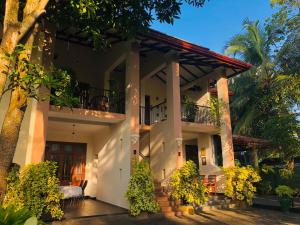 a large white house with a balcony and trees at West Dene in Negombo