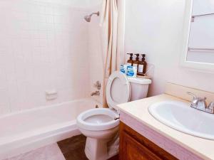a white bathroom with a toilet and a sink at Charming 3BR Retreat near Disneyland Downtown LA! in Rowland Heights