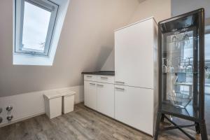 a kitchen with white cabinets and a refrigerator at Appartment Malerviertel in Braunschweig