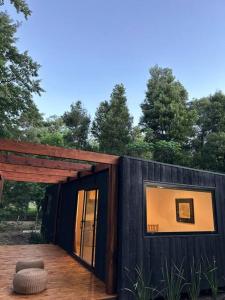 een zwart huis met een groot raam op een terras bij Cabañas en medio del bosque in Chascomús