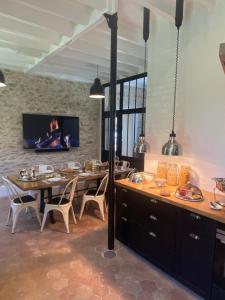 a dining room with a table and a tv at Le Clocher de la Duchesse in Bonnelles